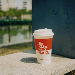 A red and white disposable cup with Chinese characters on a stone surface outdoors.
